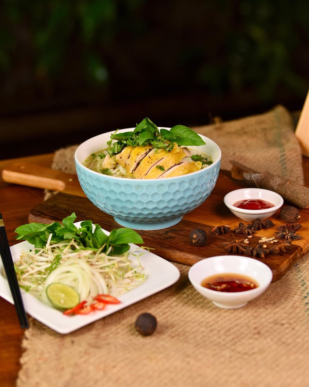 A vendor pours steaming pho broth from a copper kettle into a small bowl at an outdoor street stall in Ho Chi Minh City